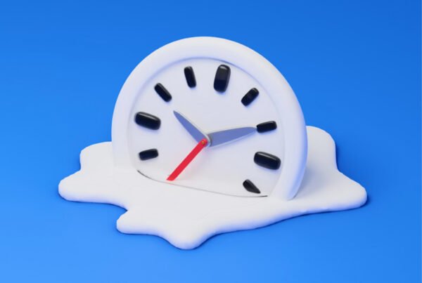 Melting white alarm clock resting on a white puddle against a bright blue background, as if time is melting away.