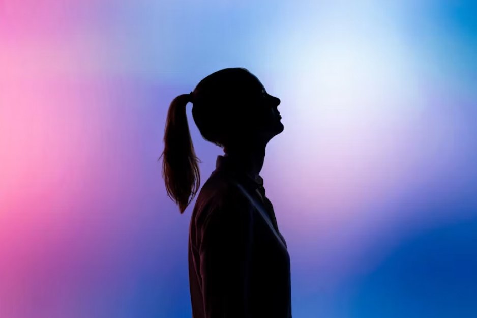 Silhouette of a person with a ponytail in profile against a pink-to-blue gradient background, creating an abstract, colorful backdrop.