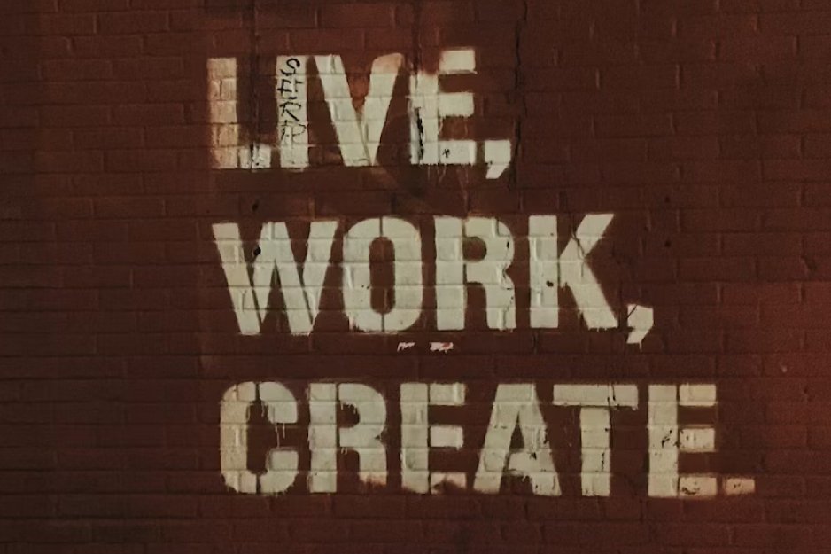 Graffiti on a red brick wall reading 'LIVE, WORK, CREATE' in large white letters.