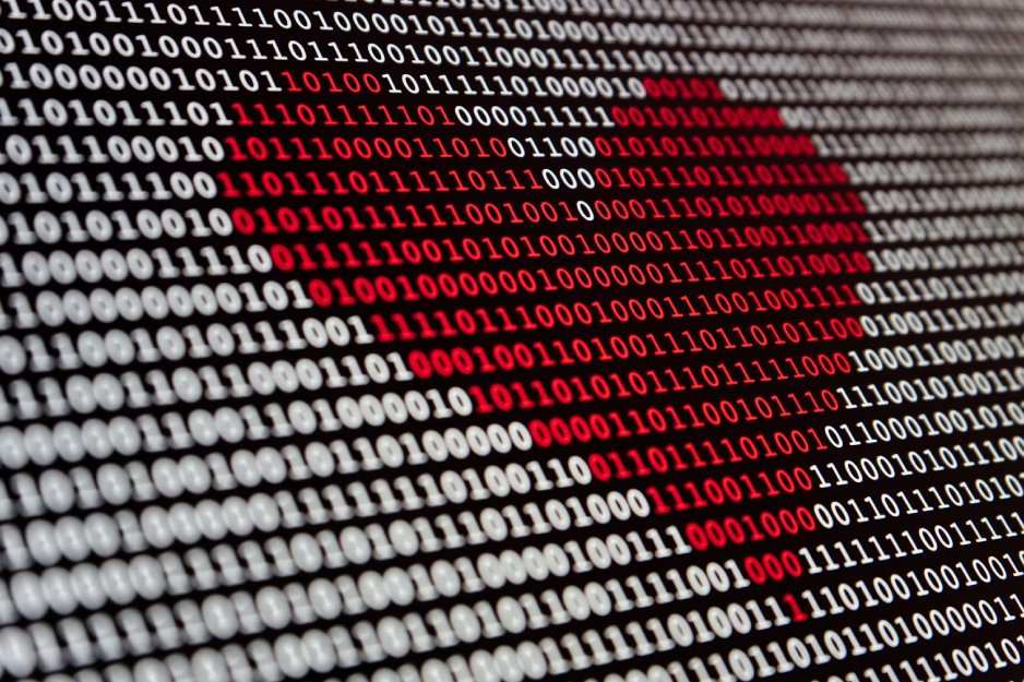 Binary code rows with a red heart shape formed by zeros and ones in a digital background.