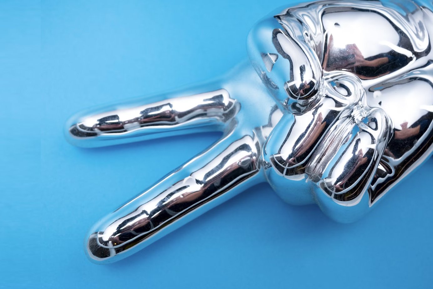 Abstract chrome sculpture with curved limbs on a blue background.