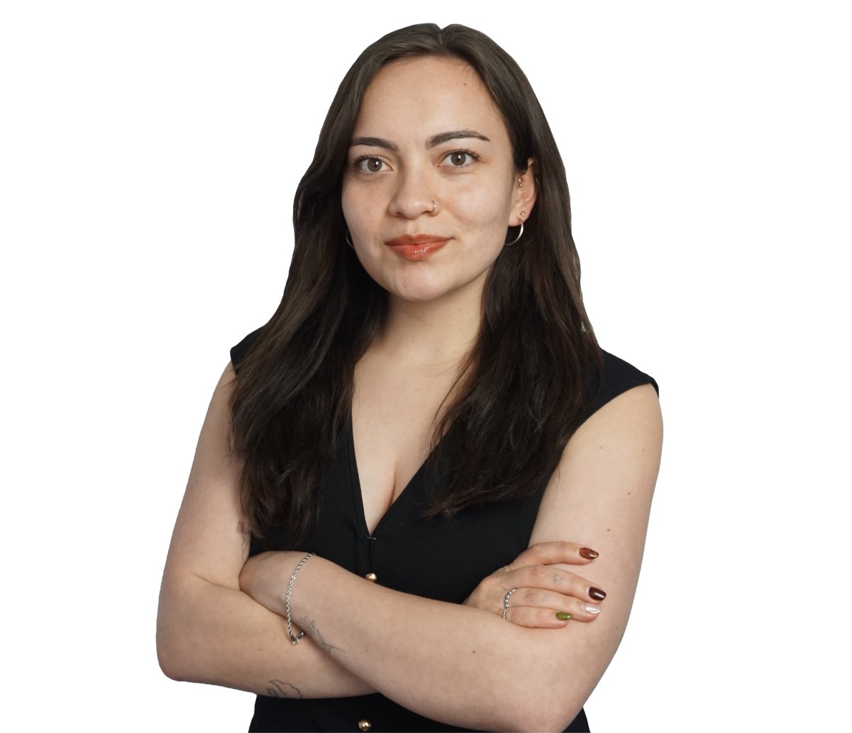 Portrait of a young woman with long dark hair in a black sleeveless top, arms crossed, looking at the camera with a slight smile.